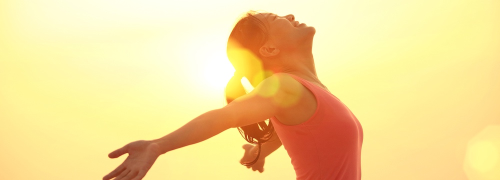 cheering woman open arms under sunrise on beach