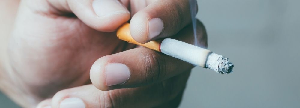 Hand holding cigarette wondering if smoking is okay after bariatric surgery