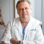 Doctor in white coat leaning against wall
