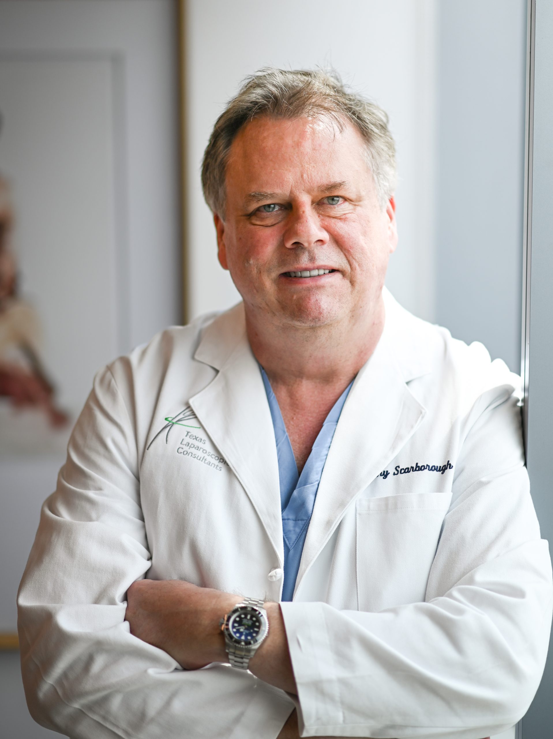 Doctor in white coat leaning against wall