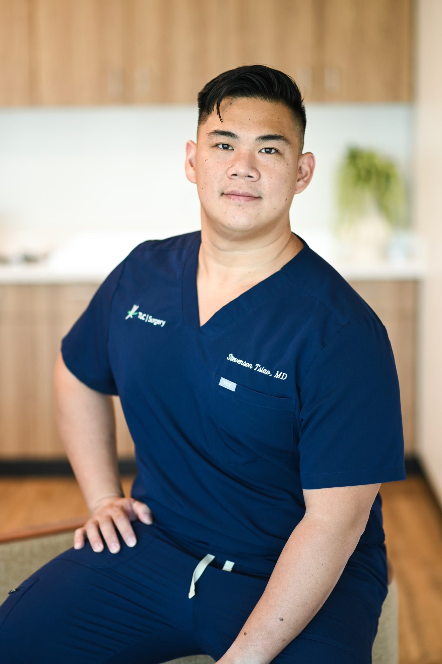 Doctor in blue scrubs sitting with hand on hip